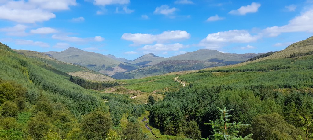 Photo of the view from Sruth Ban waterfall, looking towards the Grampian Mountains.